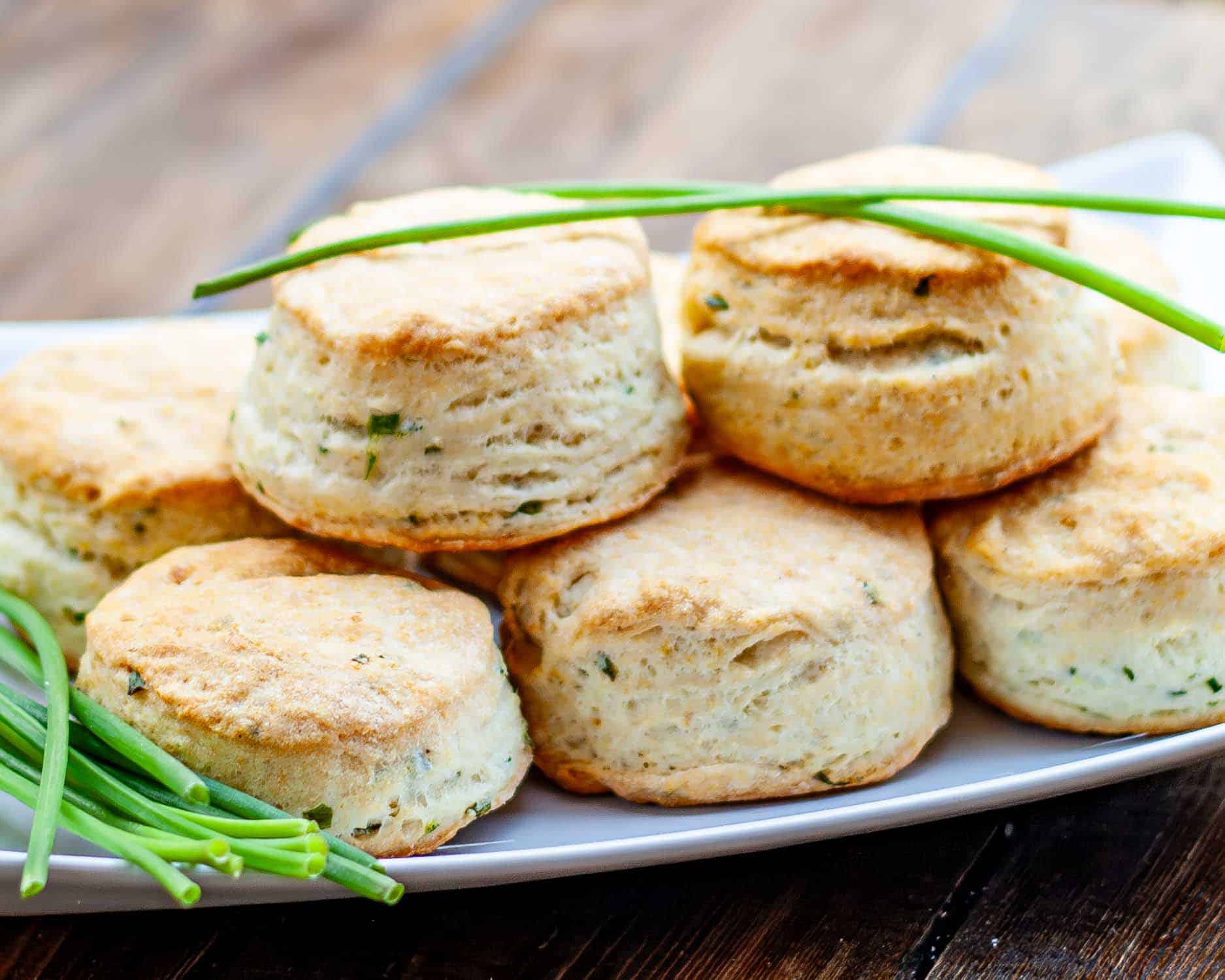 a few chive and cream cheese biscuits on a plate garnished with fresh chives.