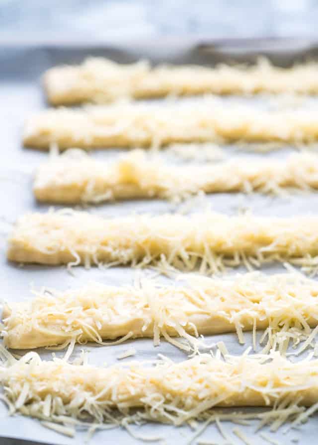 cheese sticks lines up on a baking sheet ready to go into the oven
