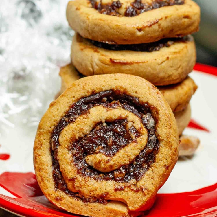 a stack of date nut pinwheel cookies on a christmas plate.