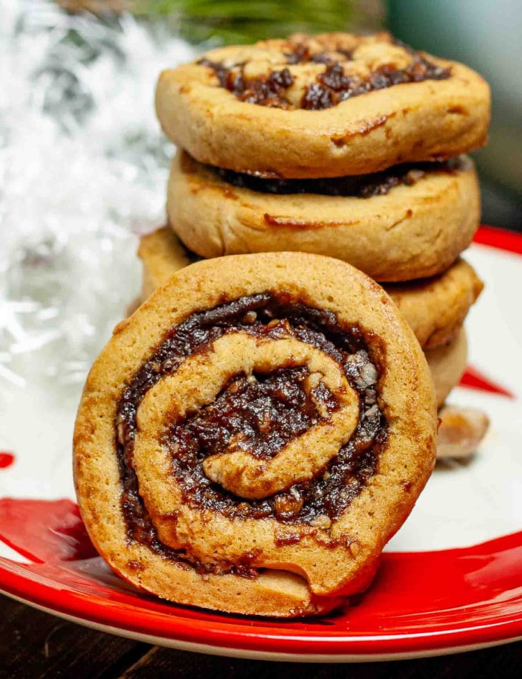 a stack of date nut pinwheel cookies on a christmas plate.