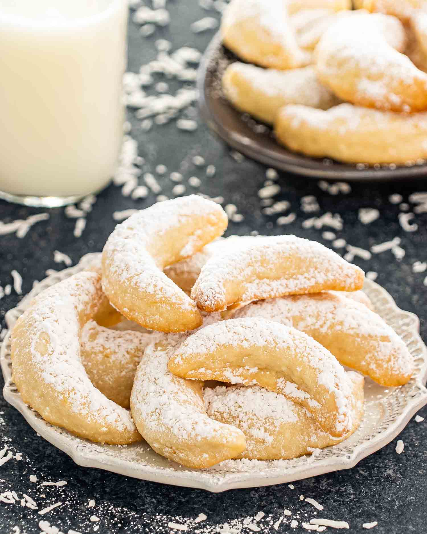 pineapple coconut crescent cookies on a plate dusted with powdered sugar.