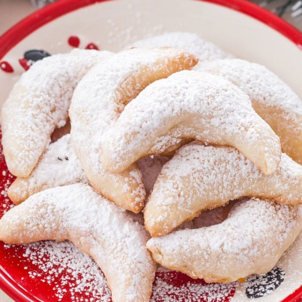 a plate of pineapple coconut crescents dusted with powdered sugar