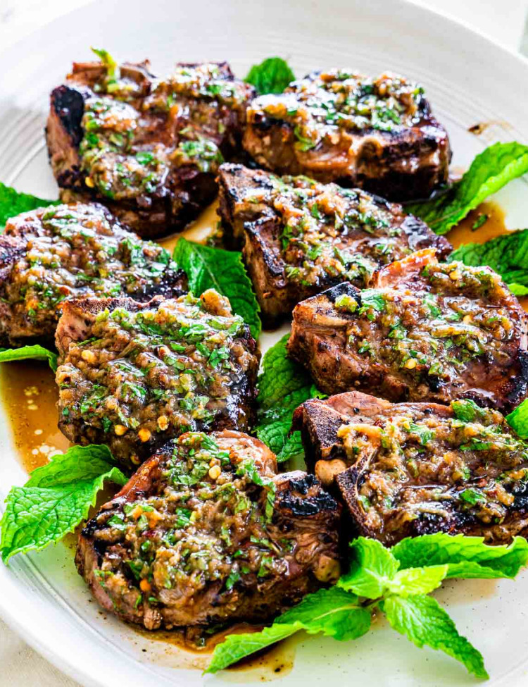 grilled lamb chops with garlic mint sauce on a platter surrounded by mint