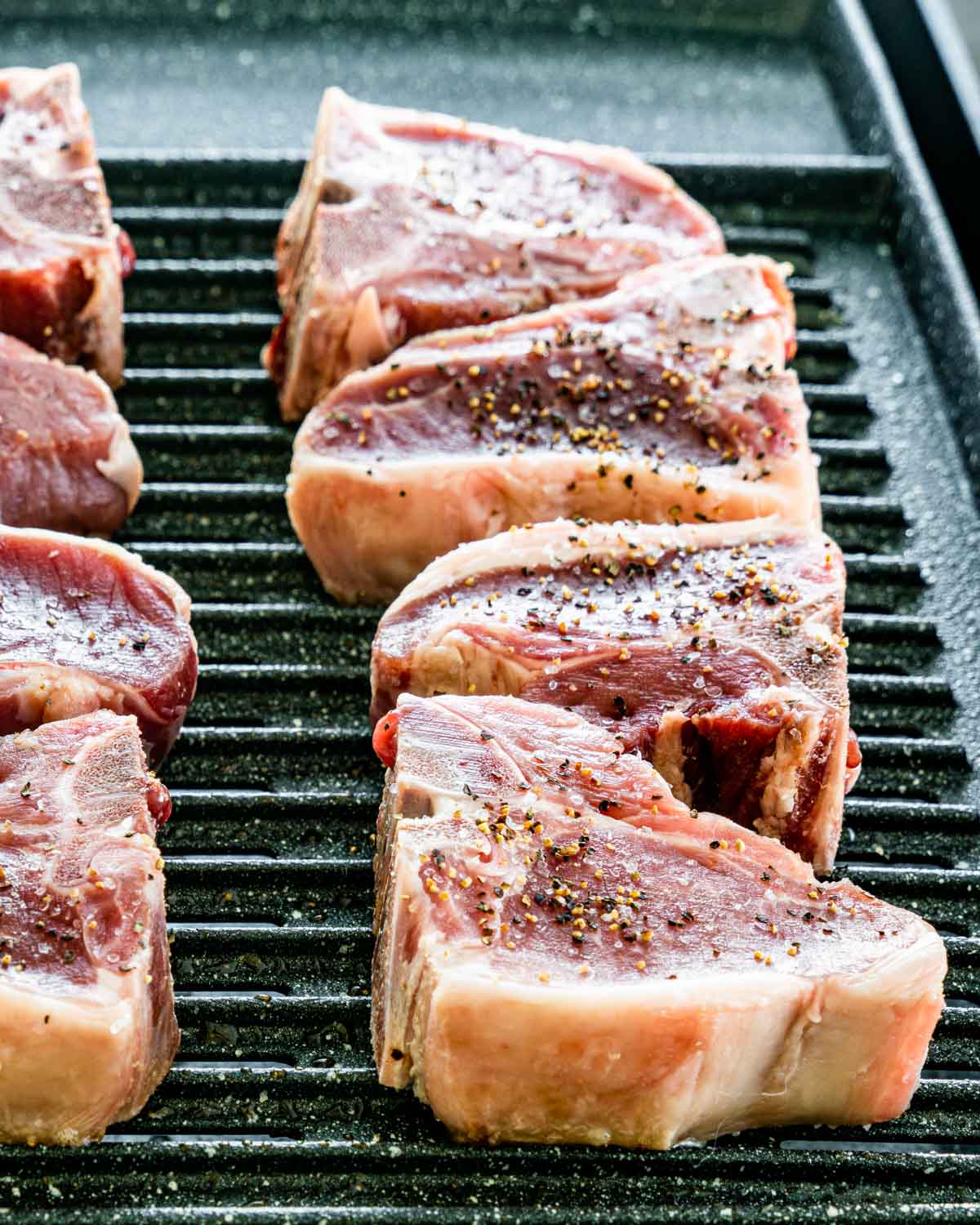 beautiful lamb loin chops on a grill seasoned with salt and pepper