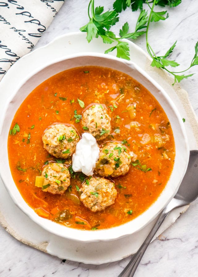 overhead of a bowl of romanian meatball soup with a dollop of sour cream