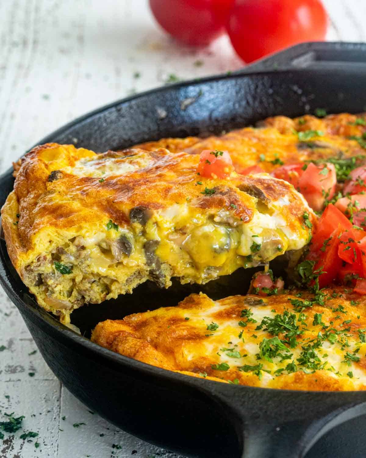 a spatula lifting a slice of sausage frittata from a skillet.