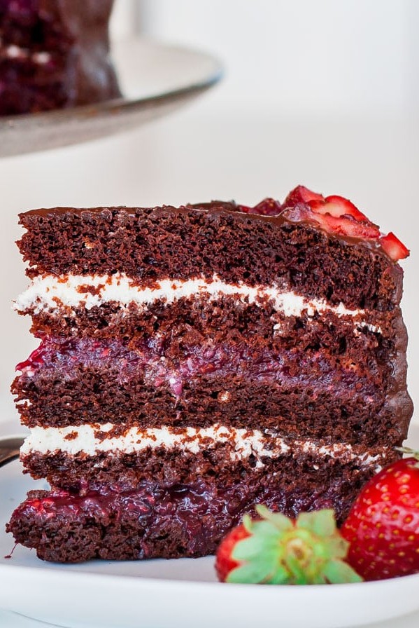 a slice of chocolate cake with mixed berry and cream cheese filling on a plate