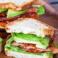 close up shot of half of an avocado blt with the center exposed
