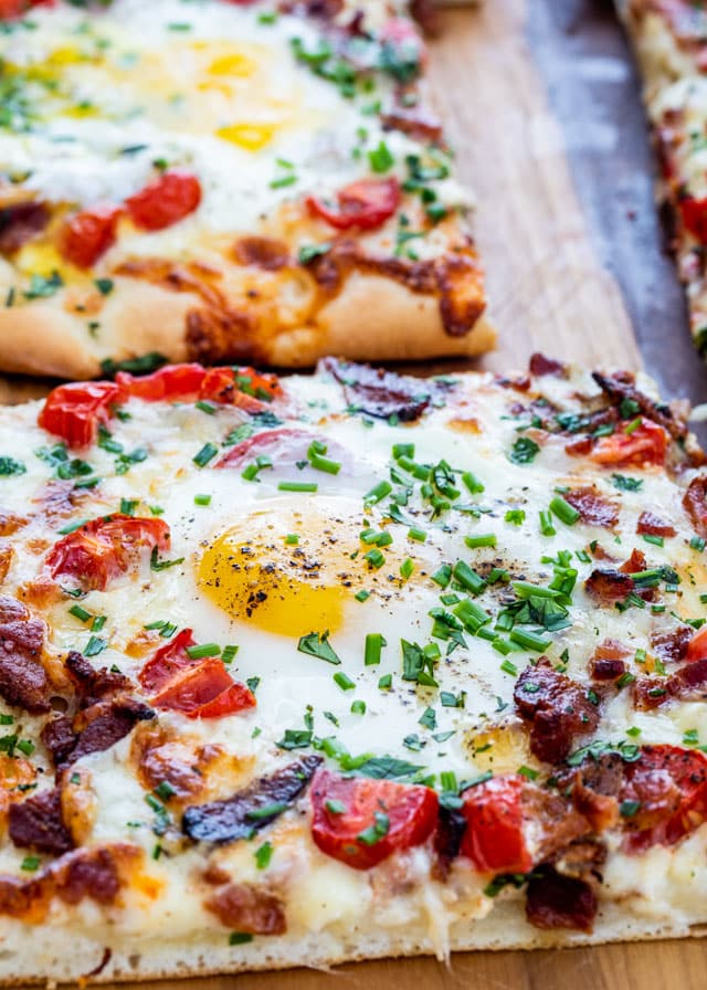 Breakfast Pizza cut into slices on a cutting board