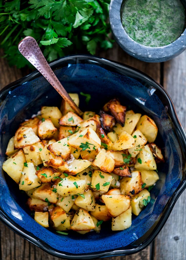 a large bowl filled with roasted cubed potatoes with a spoon