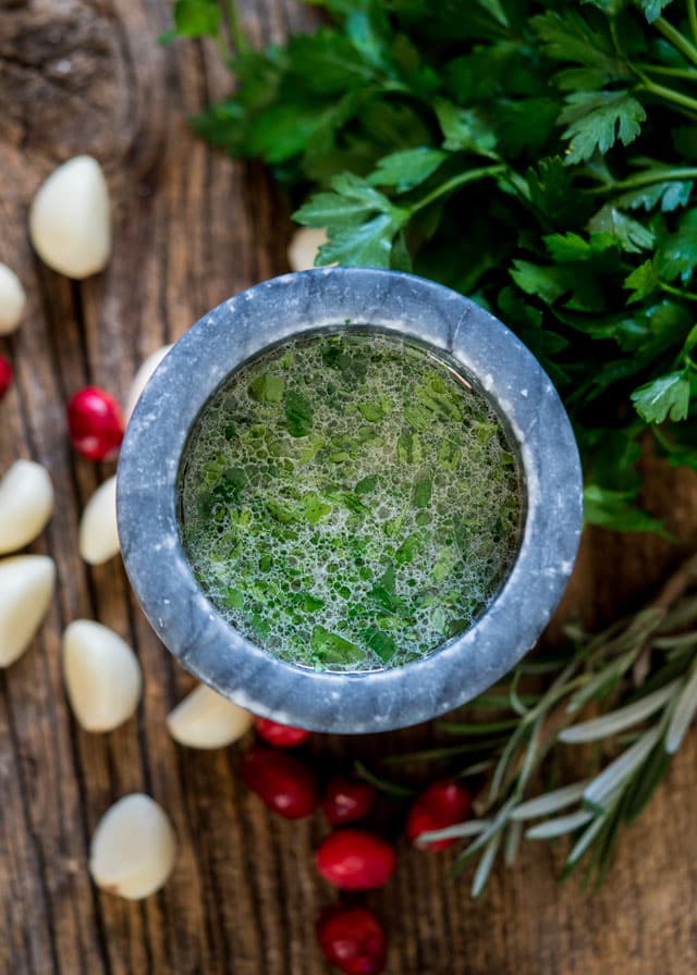 a mortar filled with fresh parsley, garlic, and water