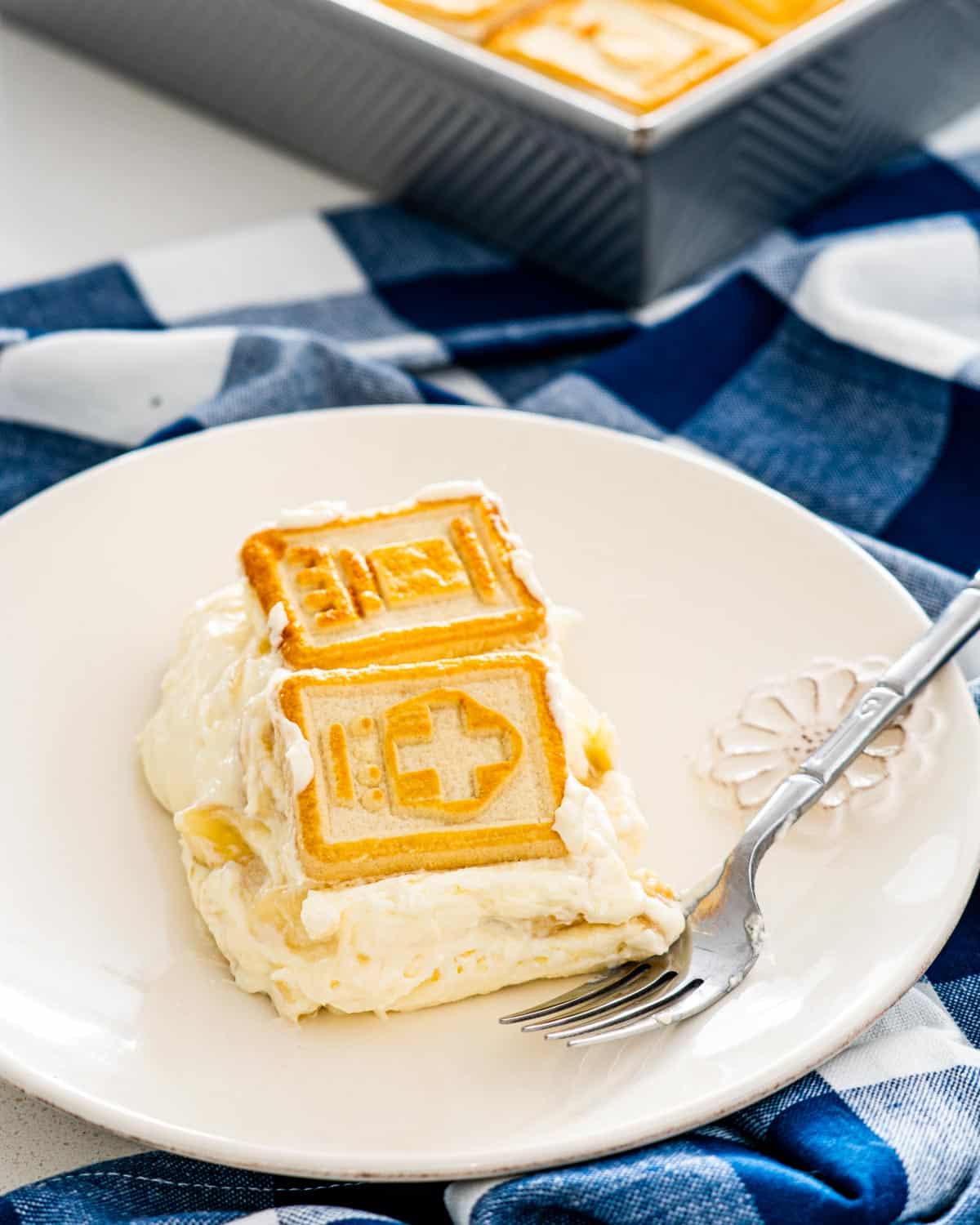 a slice of banana pudding and a fork on a white plate.