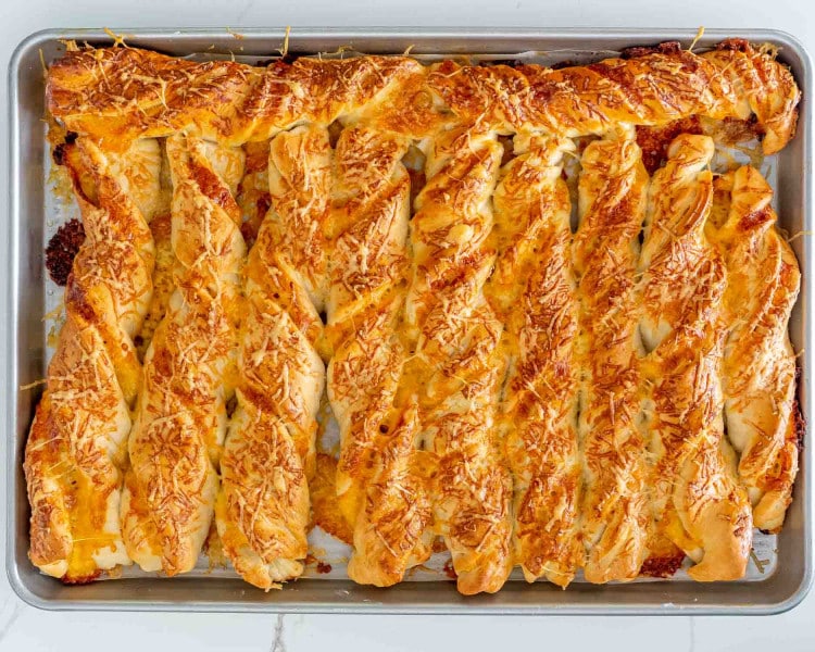 freshly baked cheesy breadsticks on a baking sheet.