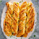 freshly baked cheesy breadsticks on a serving platter.