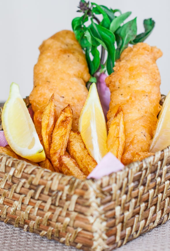 Fish and Chips in a basket with lemon wedges as garnish