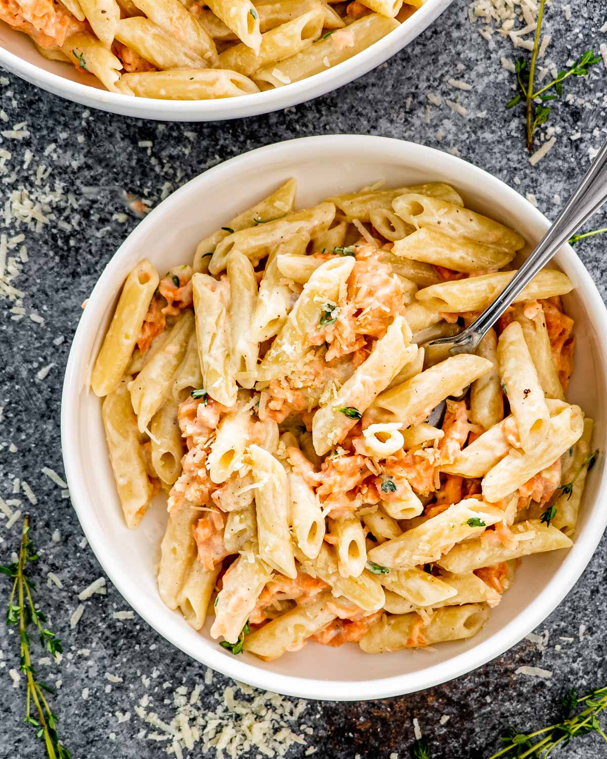 alfredo salmon pasta in a white bowl with a fork inside.