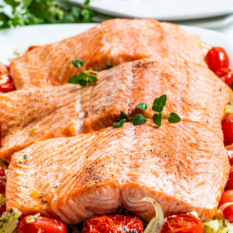baked salmon with roasted tomatoes on a white serving platter.