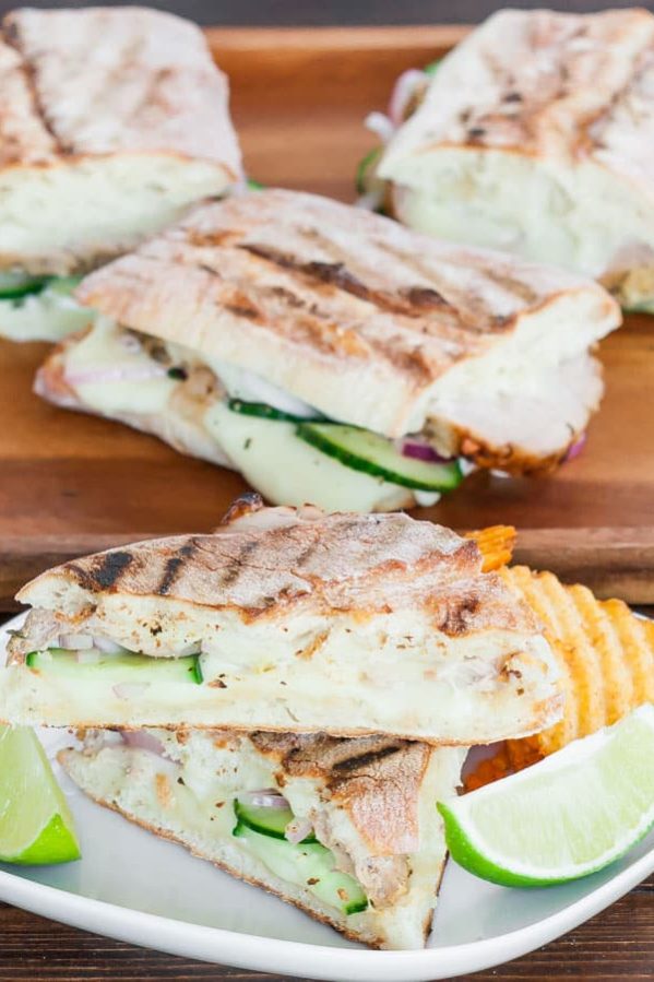 cuban panini with quick pickles on a plate garnished with lime wedges