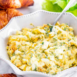 side shot of egg salad in a bowl with a spoon in it