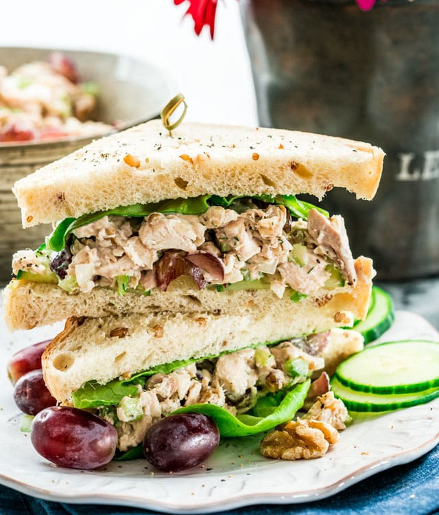 side view shot of two halves of a chicken salad sandwich stacked on a plate exposing the centers