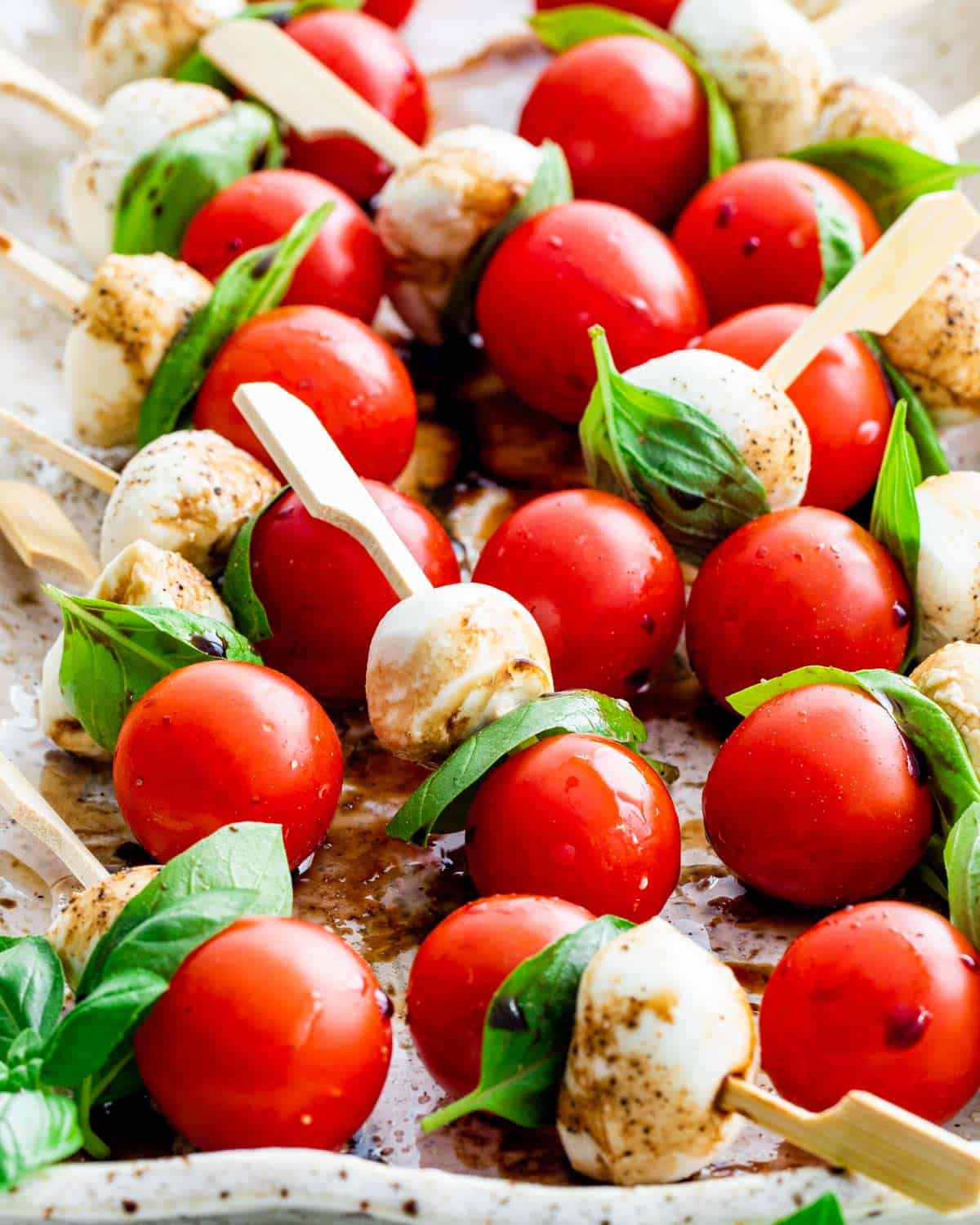 caprese salad bites on a serving platter drizzled with balsamic reduction