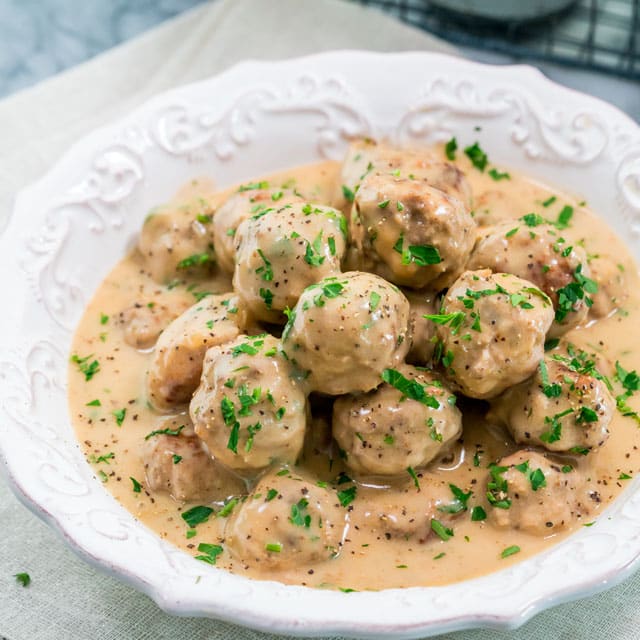 a bowl filled with swedish meatballs topped with pepper and parsley