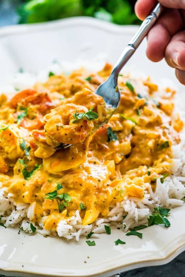 side view shot of a fork taking a bite of coconut shrimp curry and rice
