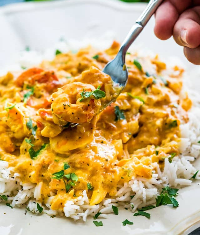 side view shot of a fork taking a bite of coconut shrimp curry and rice
