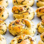 garlic knots fresh out of the oven on a baking sheet lined with parchment paper
