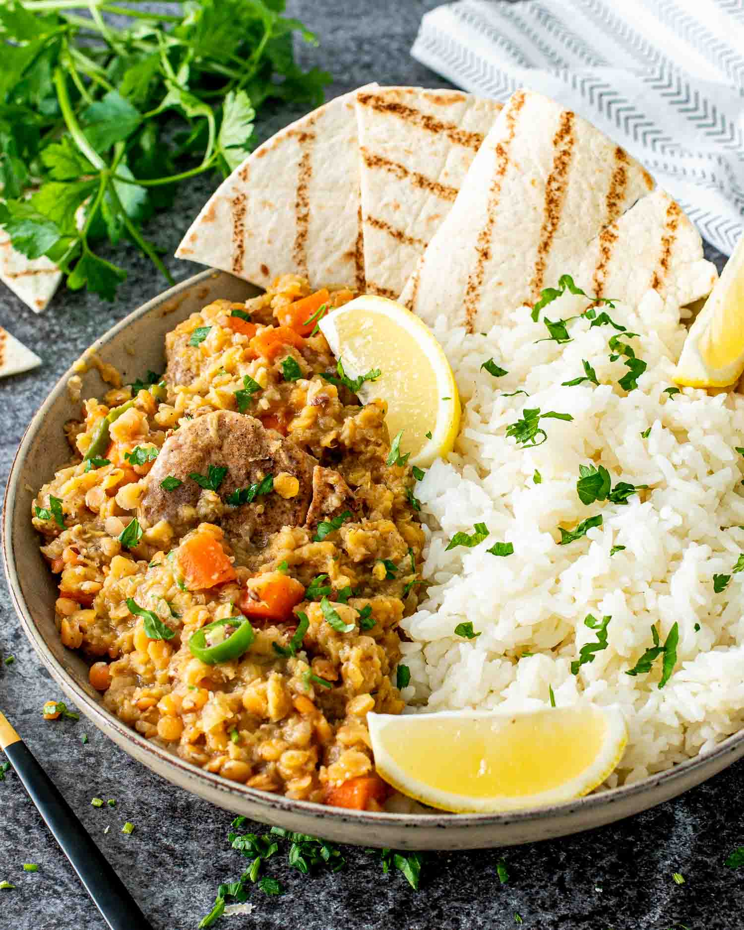indian style lentils with rice and lemon wedges in a bowl.