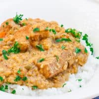 a bowl of rice topped with indian style lentils and pork