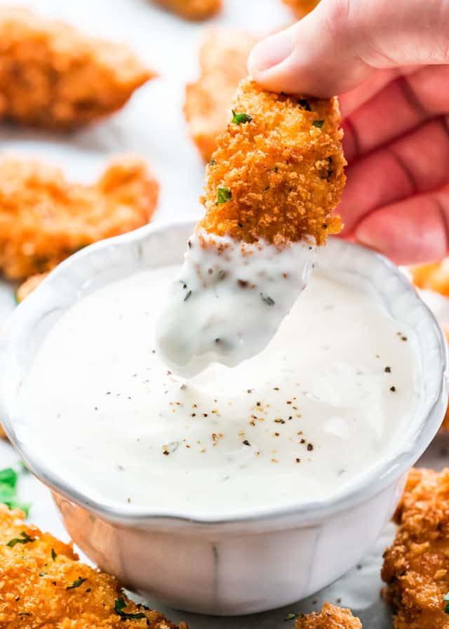 dipping a parmesan chicken strip into ranch dressing