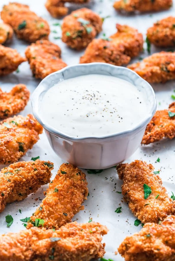 side view shot of parmesan chicken strips surrounding a small bowl of ranch
