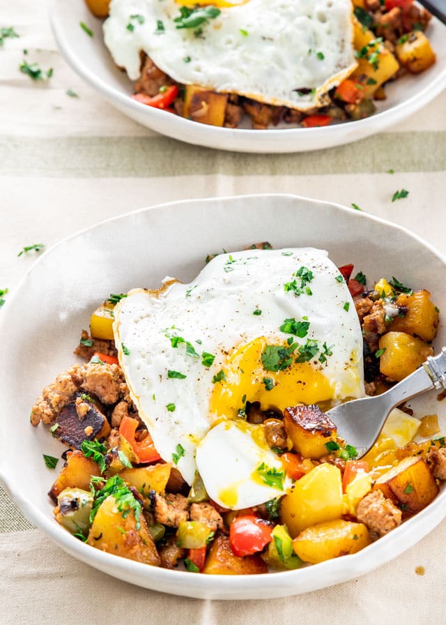 Sausage Potato Hash in a white plate with a fried egg