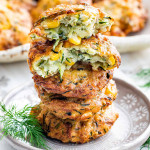 a stack of zucchini corn fritters stacked on top of each other on a plate with the top one broken in half