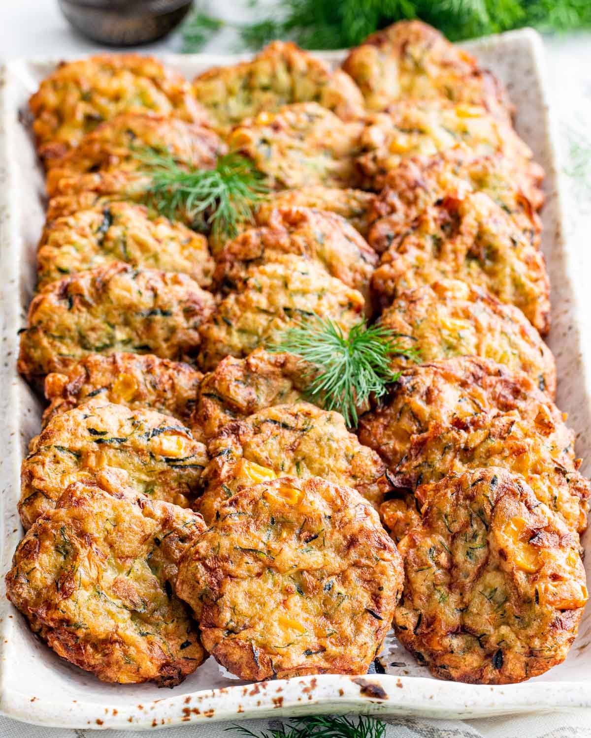 a bunch of zucchini corn fritters on a black platter