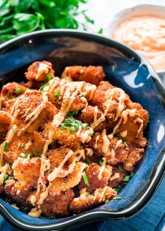 a large bowl filled with crispy bang bang chicken bites and drizzled with spicy mayo