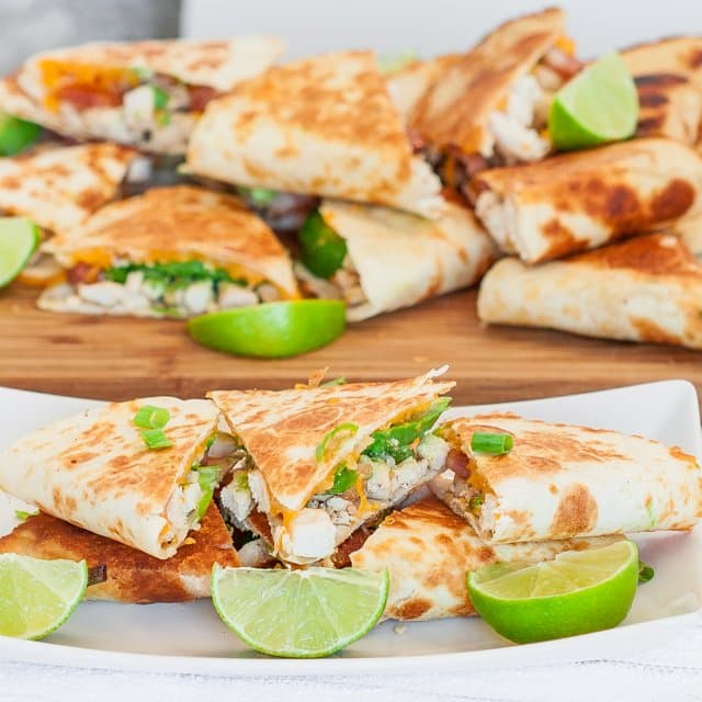 Cheesy Chicken with Bacon and Avocado Quesadillas on a plate with lime wedges as garnish