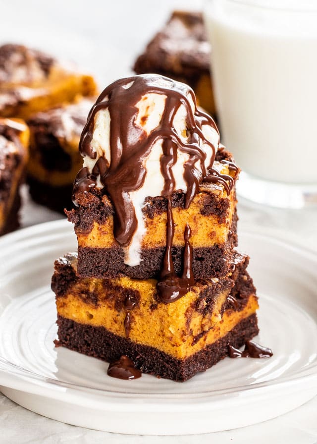 Pumpkin Cheesecake Brownies with an ice cream scoop on top and chocolate sauce