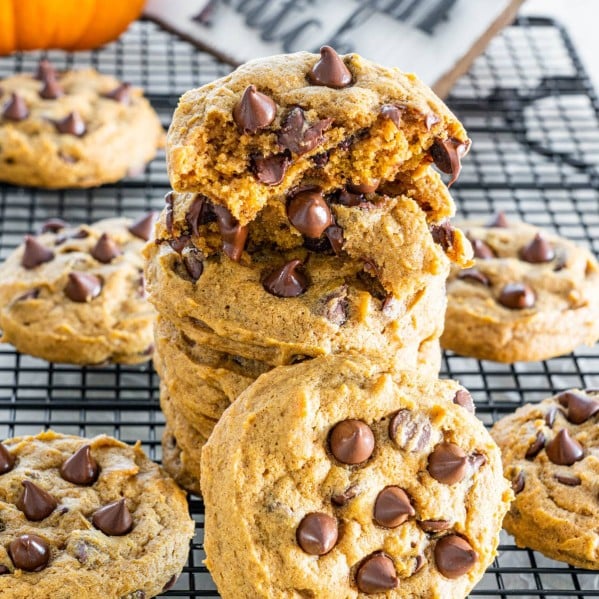 a stack of pumpkin chocolate chip cookies with the top one split in half