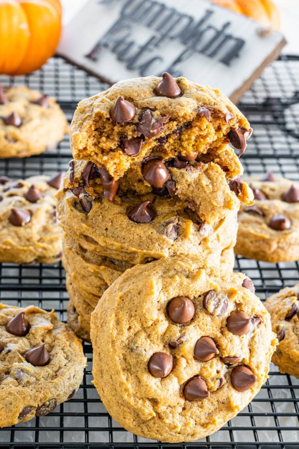 a stack of pumpkin chocolate chip cookies with the top one split in half