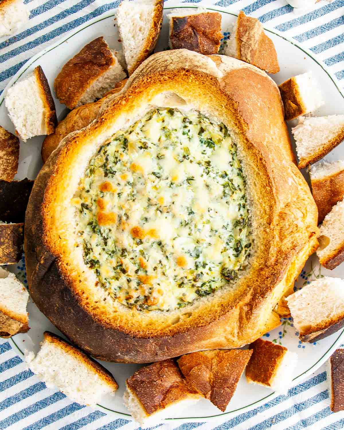 overhead shot of freshly baked spinach and artichoke dip in a bread bowl.
