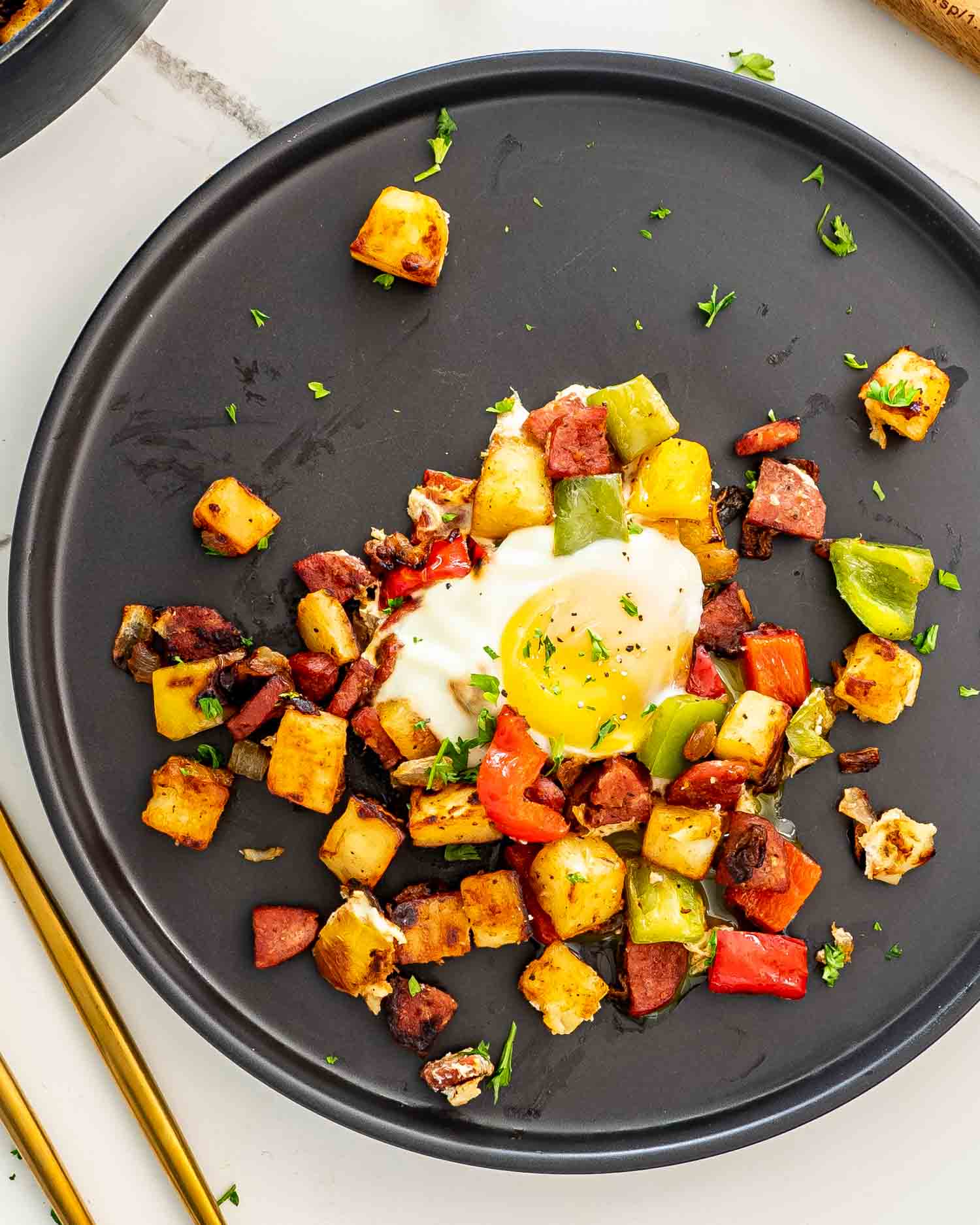 a serving of sweet potato hash with an egg on a black plate.