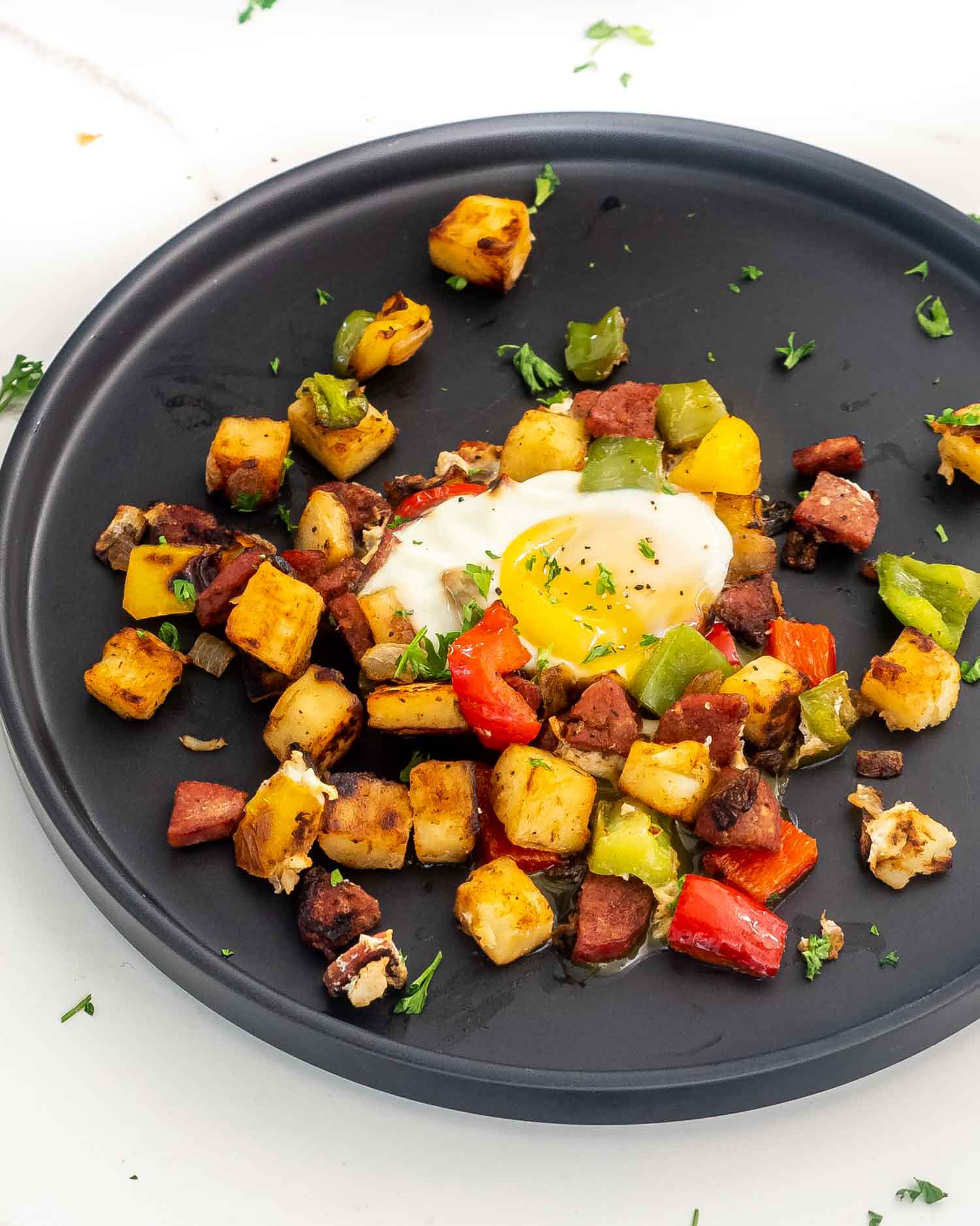 a serving of sweet potato hash with an egg on a black plate.