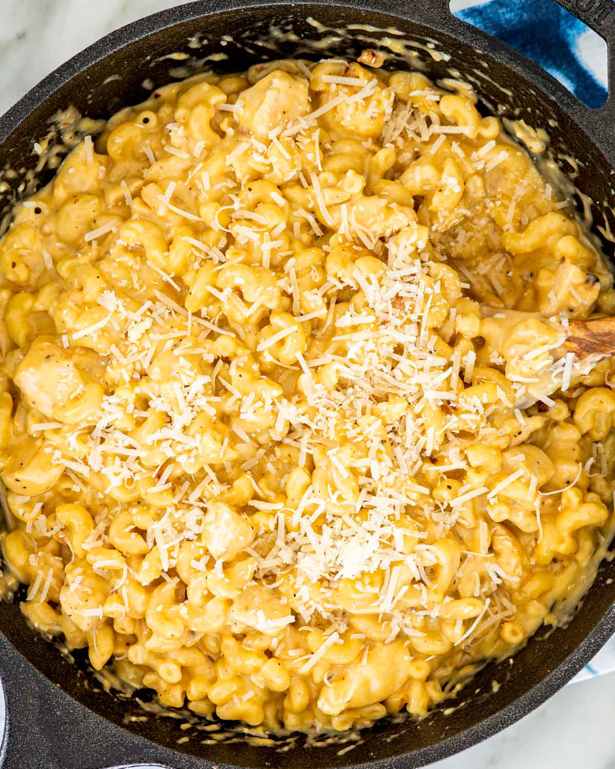 overhead shot of chicken mac and cheese in a skillet garnished with parmesan cheese