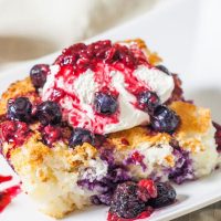 a slice of pineapple angel food cake topped with whipped cream and berries