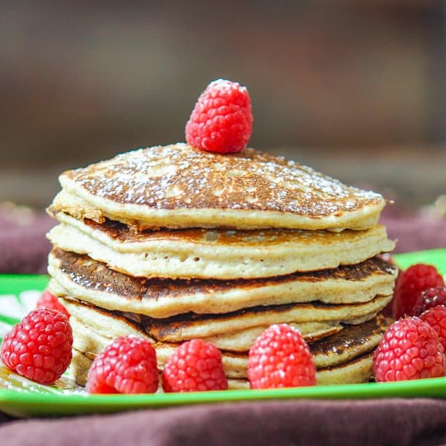 A stack of Biggest Loser Pancakes surrounded by fresh raspberries