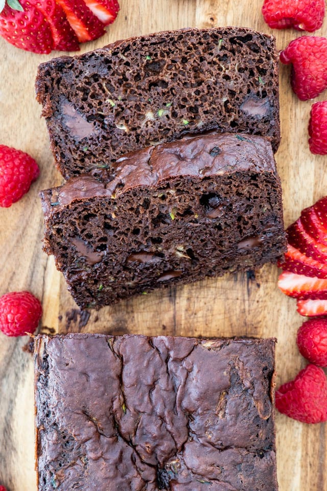 overhead shot of two pieces of chocolate zucchini bread surrounded by berries