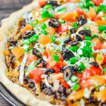 taco pizza topped with shredded lettuce chopped tomato and black olives