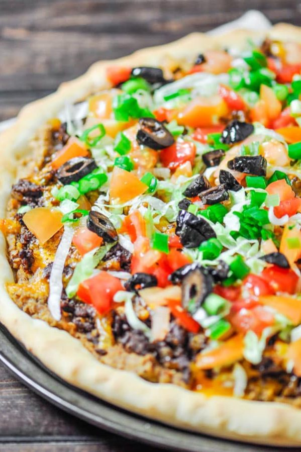 taco pizza topped with shredded lettuce chopped tomato and black olives